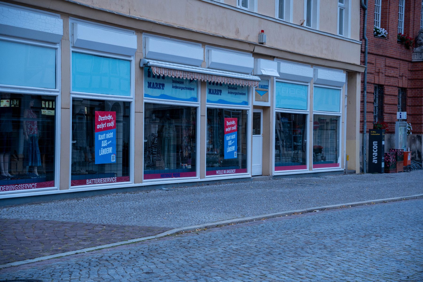 Plakate „Deutsche, wehrt euch! Kauft nicht aus anderen Ländern!“ in den Schaufenstern eines Geschäfts am Markt