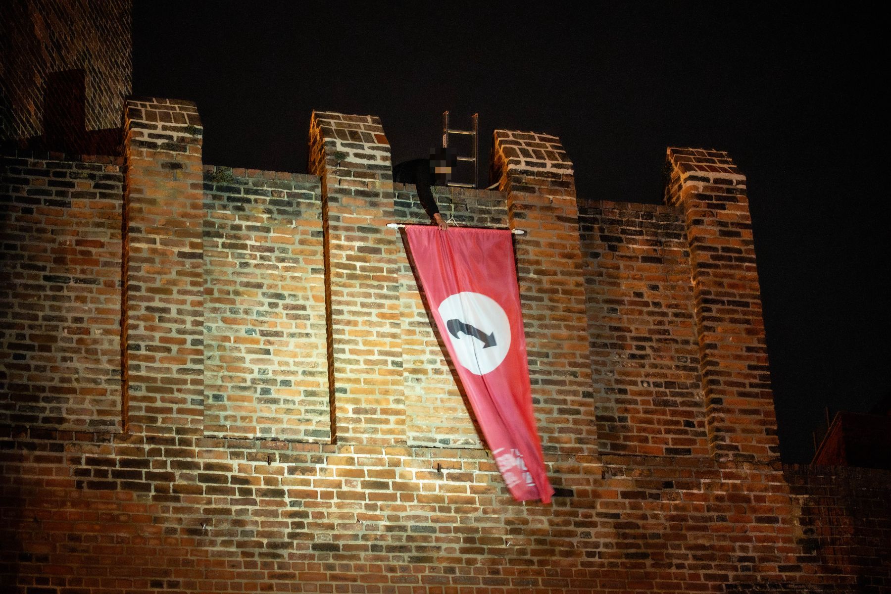 Nachts wird eine Fahne an der Stadtmauer angebracht